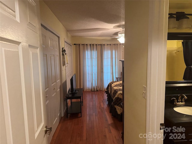 bedroom featuring wood-type flooring, a textured ceiling, ceiling fan, and sink