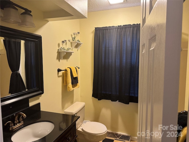 bathroom with vanity, toilet, and a textured ceiling