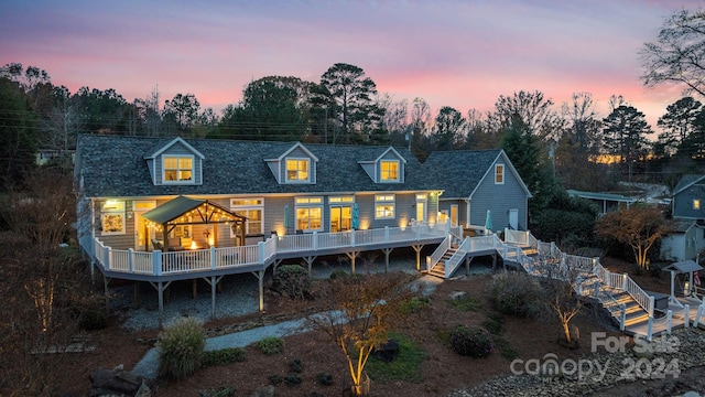 back house at dusk featuring a wooden deck