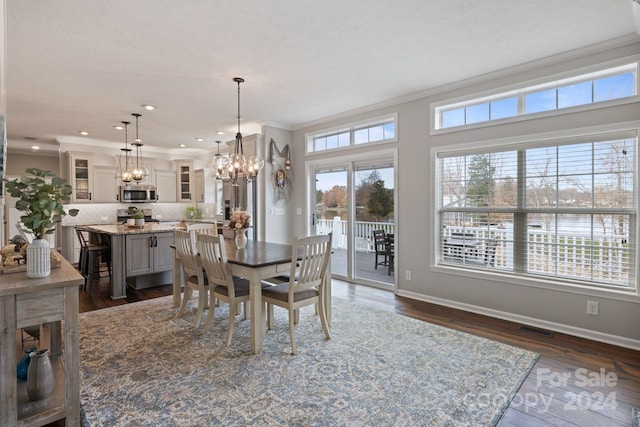 dining space with dark wood-type flooring, crown molding, a chandelier, a textured ceiling, and a water view