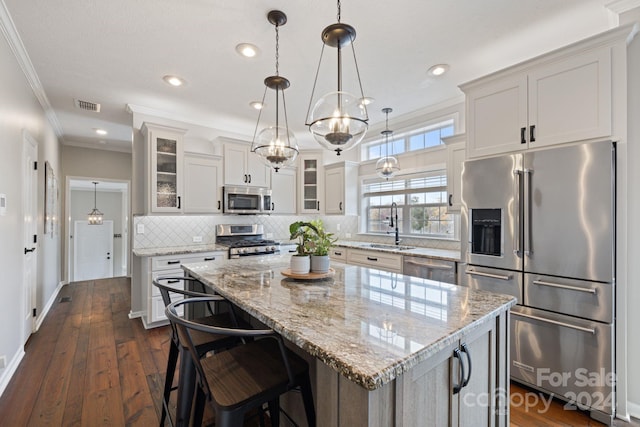 kitchen with stainless steel appliances, crown molding, white cabinets, dark hardwood / wood-style floors, and a kitchen island