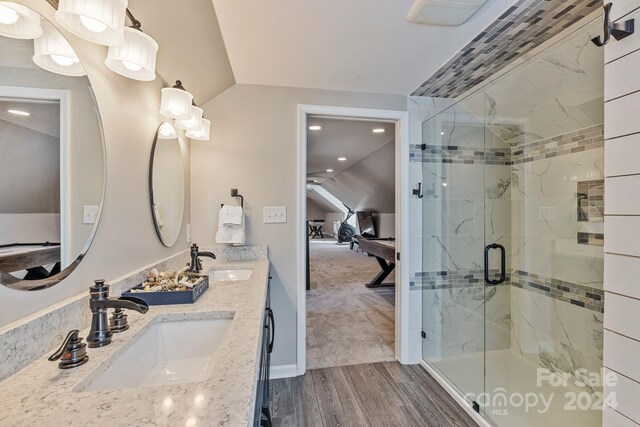 bathroom featuring hardwood / wood-style flooring, vanity, walk in shower, and vaulted ceiling