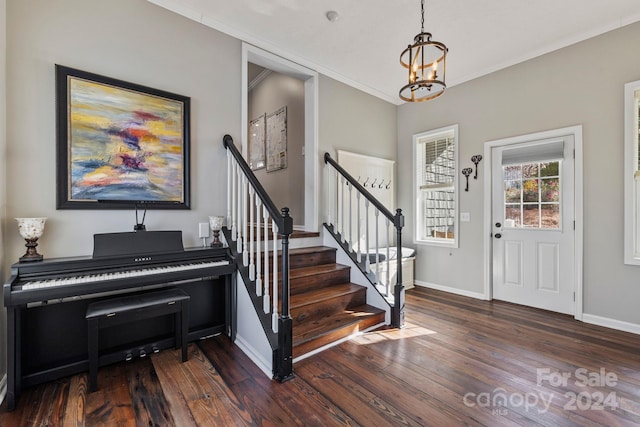 entrance foyer with crown molding, dark wood-type flooring, and an inviting chandelier