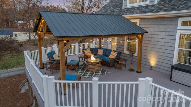 deck at dusk featuring a gazebo and an outdoor living space with a fire pit