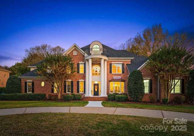 view of front of property featuring a lawn and a balcony