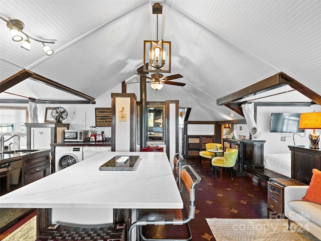 dining room with ceiling fan, dark wood-type flooring, sink, washer / dryer, and lofted ceiling