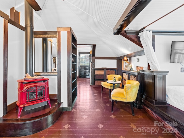 living area featuring dark hardwood / wood-style floors, a wood stove, and vaulted ceiling