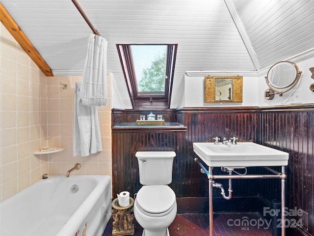 full bathroom featuring sink, vaulted ceiling with skylight, shower / bath combination with curtain, and toilet