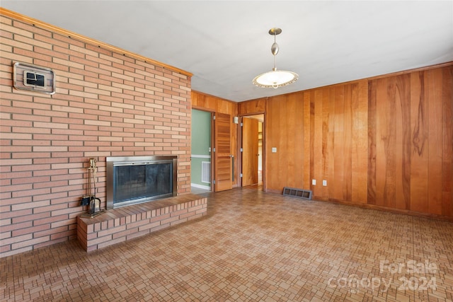 unfurnished living room featuring brick wall, a fireplace, and wood walls