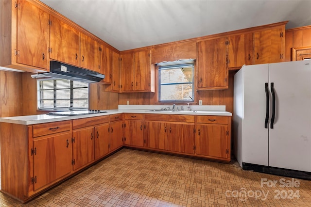 kitchen with sink, white fridge, black gas stovetop, and range hood