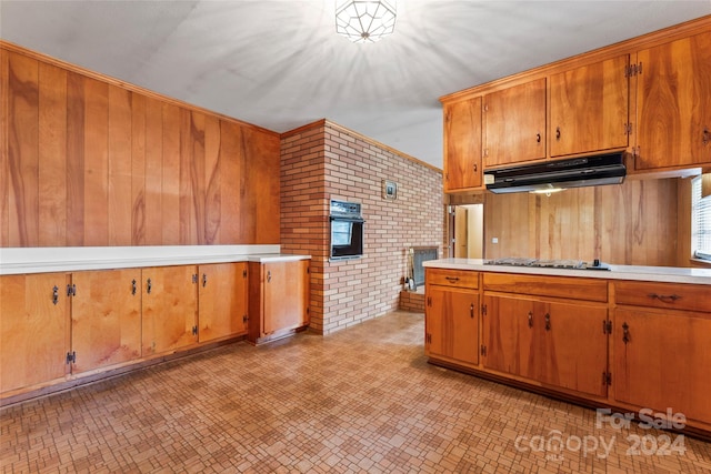 kitchen with oven, exhaust hood, brick wall, and gas cooktop