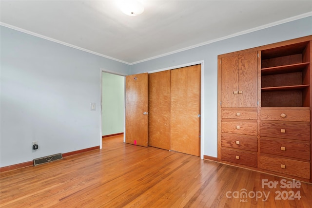 unfurnished bedroom with crown molding and light wood-type flooring