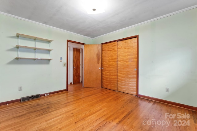 unfurnished bedroom with a closet, ornamental molding, and light hardwood / wood-style flooring