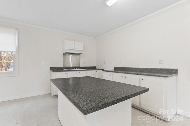 kitchen with stainless steel gas cooktop, white cabinetry, a kitchen island, and ornamental molding