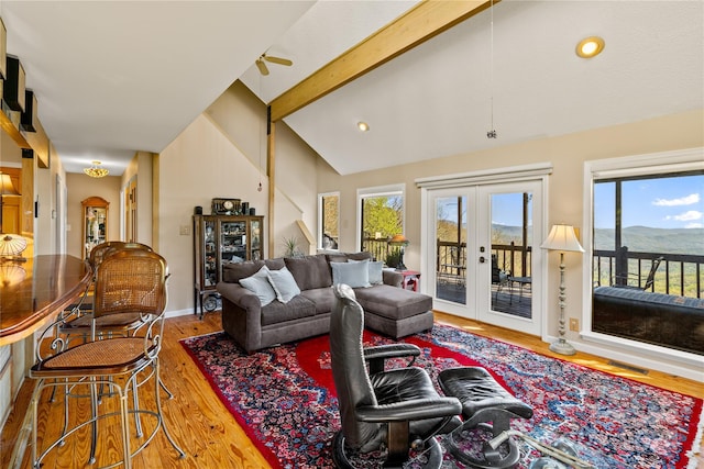 living room with french doors, ceiling fan, lofted ceiling with beams, hardwood / wood-style flooring, and a mountain view