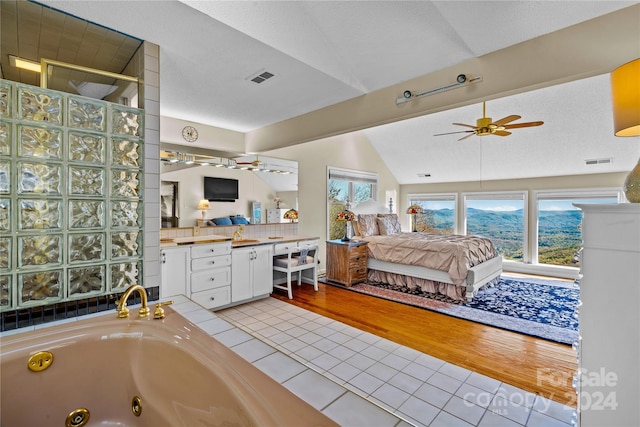 bathroom with hardwood / wood-style floors, vanity, vaulted ceiling, ceiling fan, and a tub to relax in