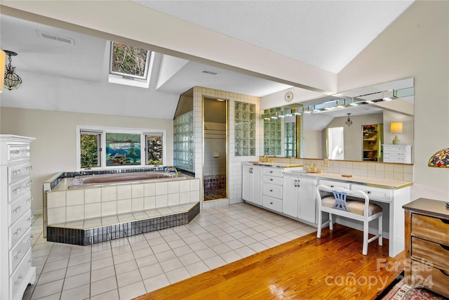 bathroom featuring backsplash, lofted ceiling with skylight, wood-type flooring, a textured ceiling, and vanity