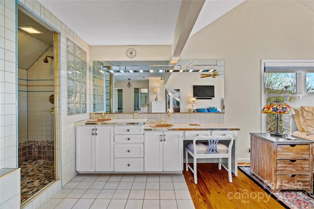 bathroom featuring tile patterned flooring, a textured ceiling, vanity, and a shower with door