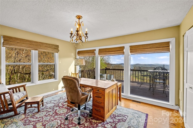 office area with a chandelier, light hardwood / wood-style floors, and a textured ceiling