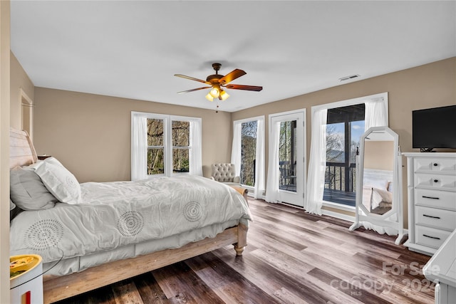 bedroom with hardwood / wood-style floors, access to outside, multiple windows, and ceiling fan