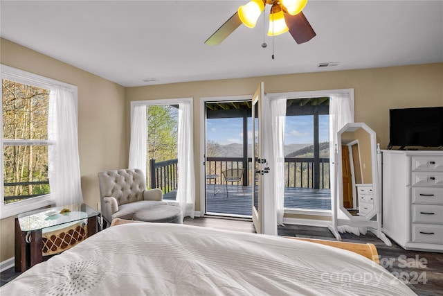 bedroom featuring ceiling fan, access to exterior, wood-type flooring, and multiple windows