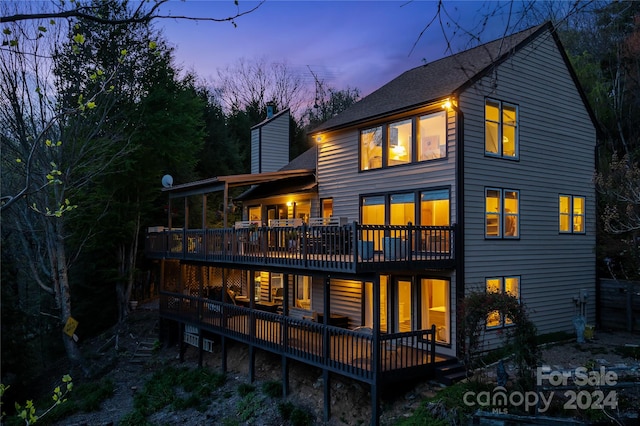 back house at dusk featuring a deck