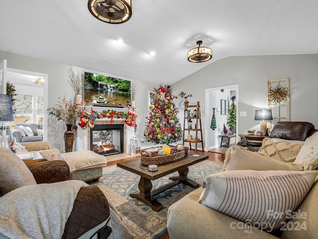 living room with a multi sided fireplace, lofted ceiling, and hardwood / wood-style flooring