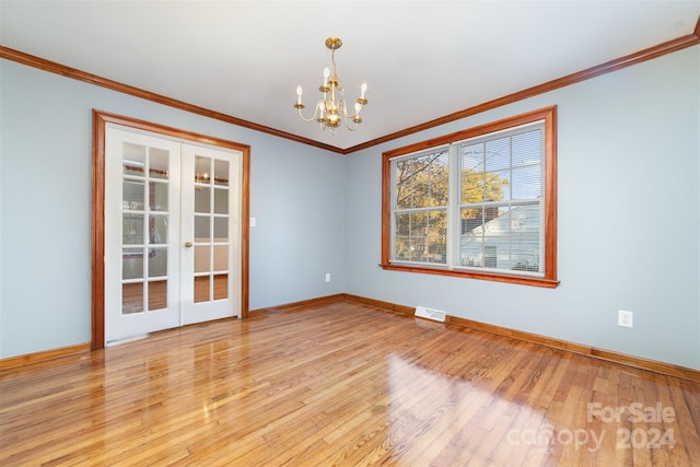 unfurnished room with an inviting chandelier, french doors, ornamental molding, and light hardwood / wood-style flooring