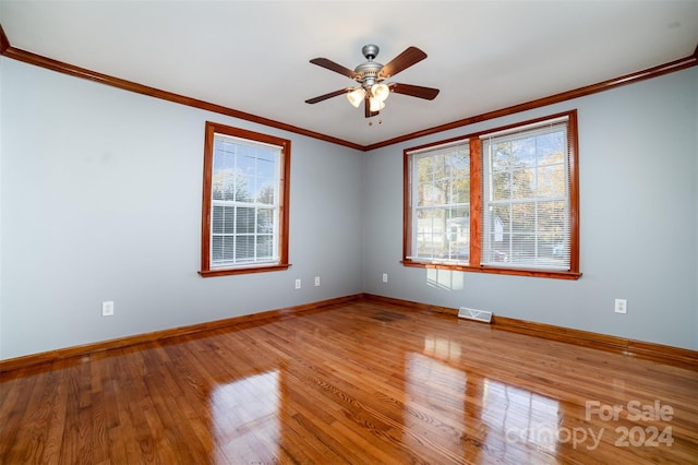 unfurnished room featuring hardwood / wood-style floors, crown molding, ceiling fan, and a healthy amount of sunlight