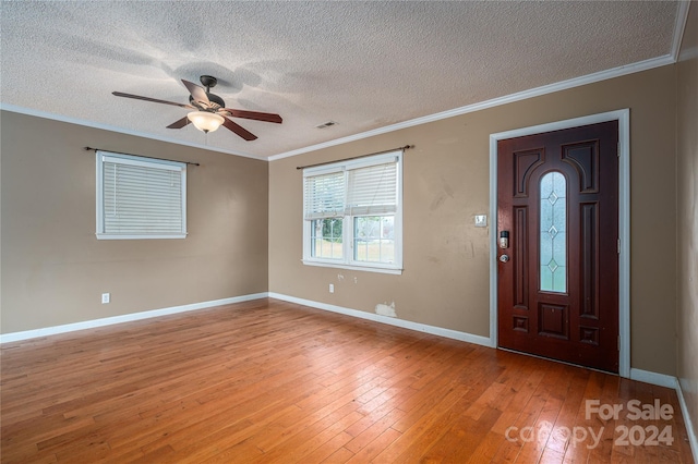 entryway featuring ceiling fan, crown molding, a textured ceiling, and light hardwood / wood-style flooring