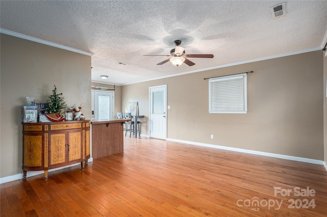 living room featuring hardwood / wood-style floors, ornamental molding, and a textured ceiling