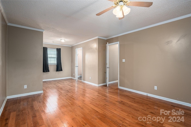 empty room with wood-type flooring, a textured ceiling, ceiling fan, and crown molding