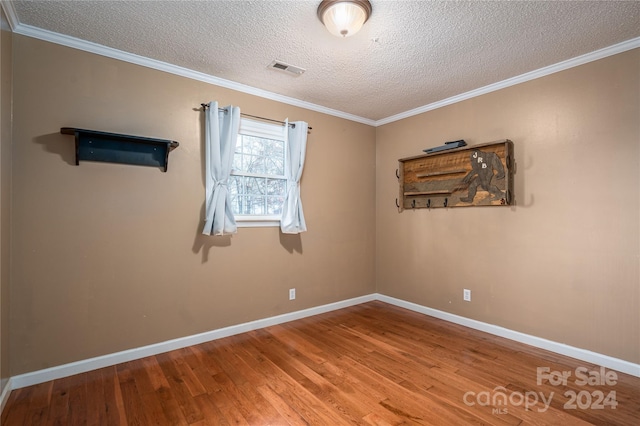 empty room with wood-type flooring, a textured ceiling, and ornamental molding