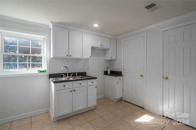 kitchen featuring white cabinetry, sink, light tile patterned floors, and crown molding