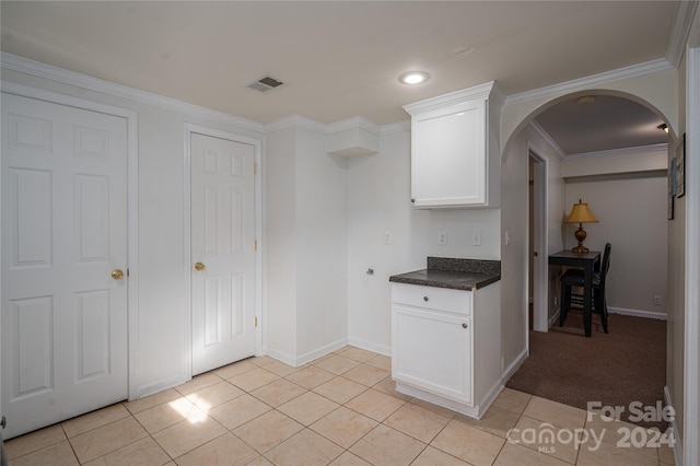 kitchen with white cabinetry, ornamental molding, and light tile patterned floors