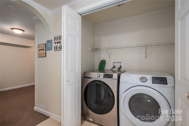 laundry room featuring light carpet, ornamental molding, and washing machine and clothes dryer