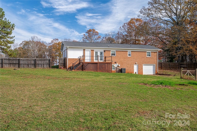 rear view of property featuring a lawn, a wooden deck, cooling unit, and a garage