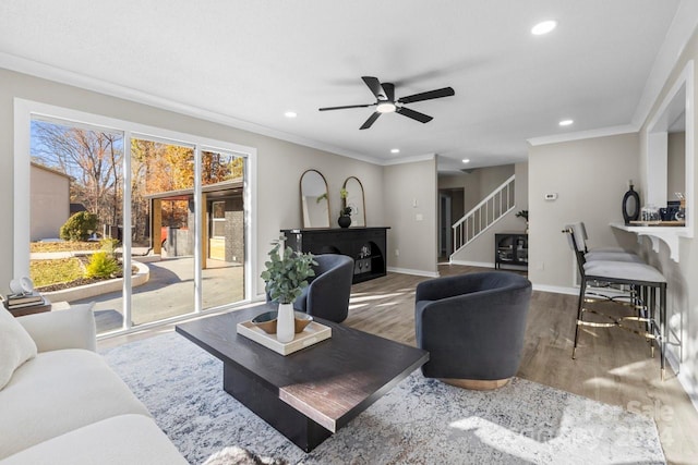 living room with hardwood / wood-style floors, ceiling fan, ornamental molding, and a fireplace