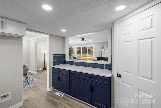 kitchen with ornamental molding, a textured ceiling, blue cabinets, ceiling fan, and light hardwood / wood-style floors