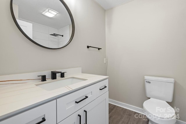 bathroom with hardwood / wood-style floors, vanity, a textured ceiling, and toilet