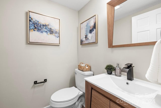 bathroom featuring a textured ceiling, vanity, and toilet