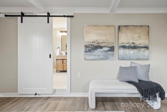 sitting room with beamed ceiling, hardwood / wood-style floors, and a barn door