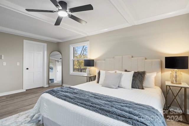 bedroom with hardwood / wood-style floors, ceiling fan, and beam ceiling