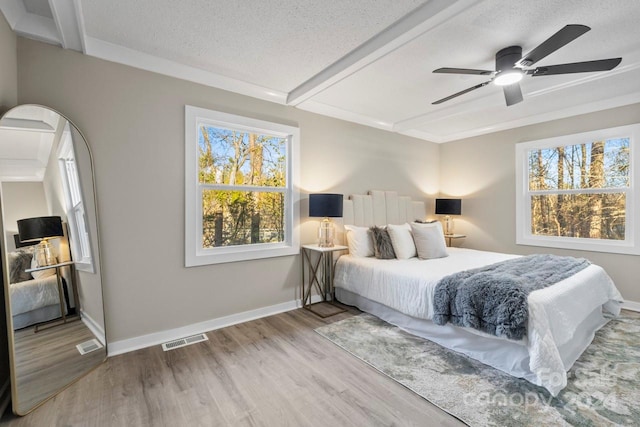 bedroom with ceiling fan, light wood-type flooring, a textured ceiling, and multiple windows