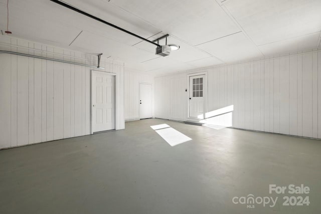 garage with wood walls and a garage door opener