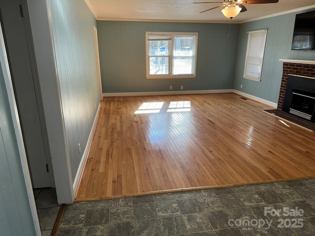 unfurnished living room with a fireplace, ceiling fan, ornamental molding, and wood walls