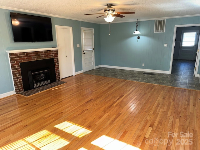 unfurnished living room featuring ceiling fan, a fireplace, dark wood-type flooring, and a textured ceiling