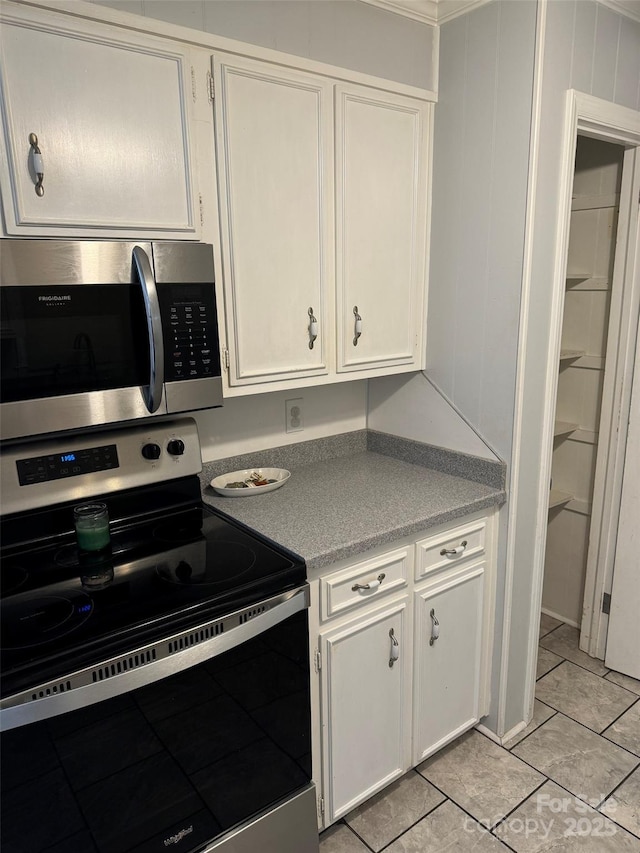 kitchen featuring appliances with stainless steel finishes, light tile patterned floors, and white cabinetry