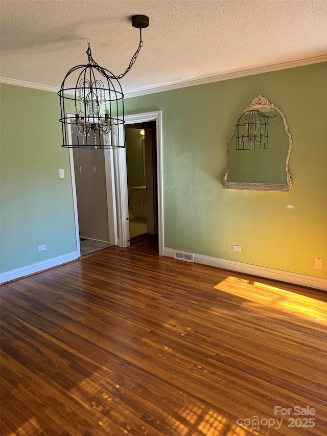 unfurnished dining area featuring dark hardwood / wood-style flooring, ornamental molding, a textured ceiling, and a notable chandelier