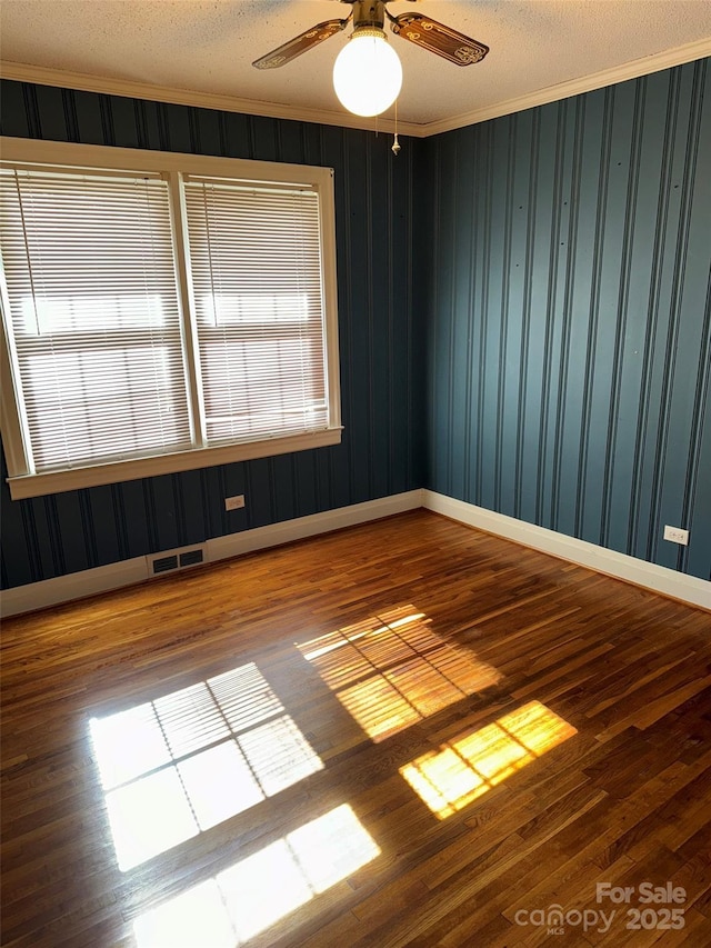 spare room with crown molding, ceiling fan, wood-type flooring, and a textured ceiling